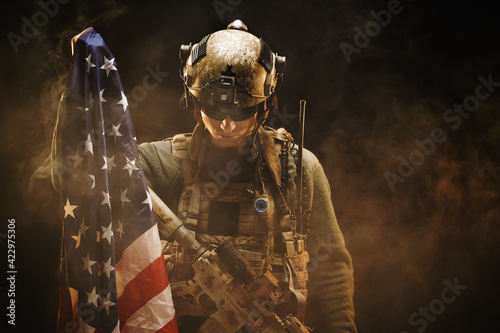Special forces soldier holding US national flag in the dark photo