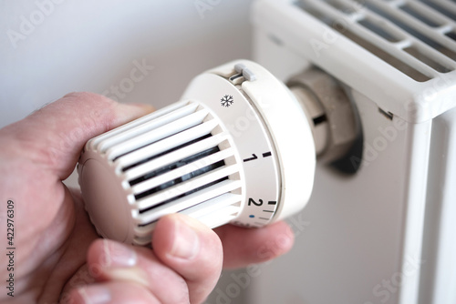 close-up of person turning thermostat on radiator to anti frost protection