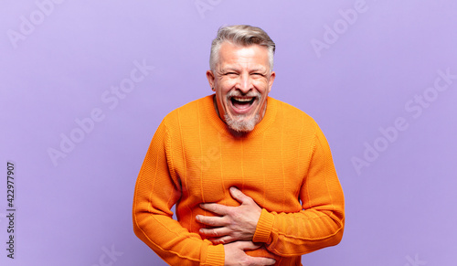 old senior man laughing out loud at some hilarious joke, feeling happy and cheerful, having fun