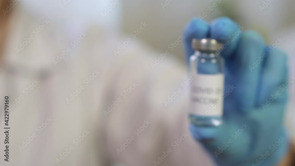The doctor female pharmacist shows a vaccine against the COVID-19 coronavirus into the camera. The doctor female pharmacist shows a vaccine against the COVID-19 coronavirus into the camera.