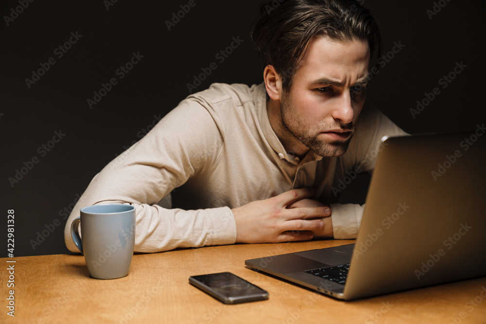 Serious pensive brunette businessman working on laptop Serious pensive brunette businessman working on laptop