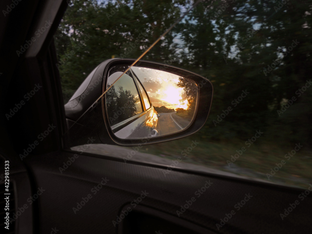 sunset and road in the rearview mirror