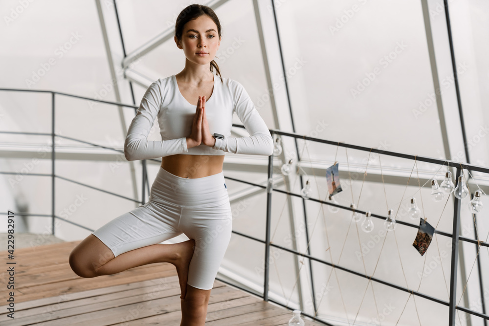Young white woman doing exercise during yoga practice indoors