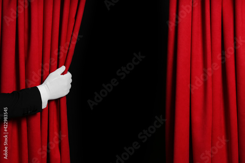 Person opening red front curtains on black background, closeup. Space for text