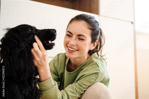 Happy young brunette woman with her dog at home