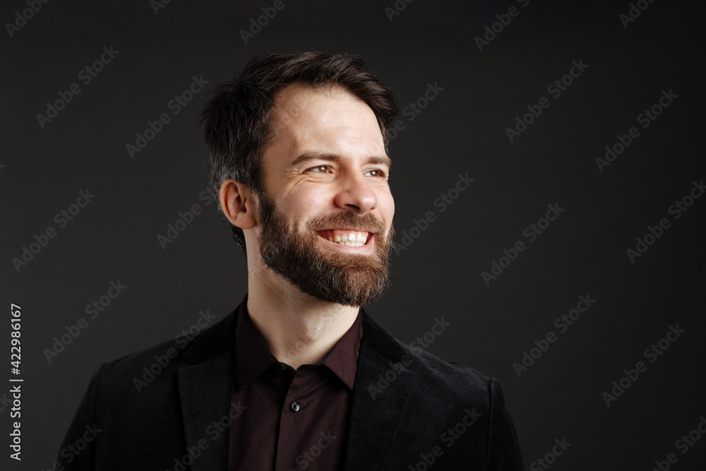 Bearded happy man in black jacket smiling and looking aside Bearded happy man in black jacket smiling and looking aside