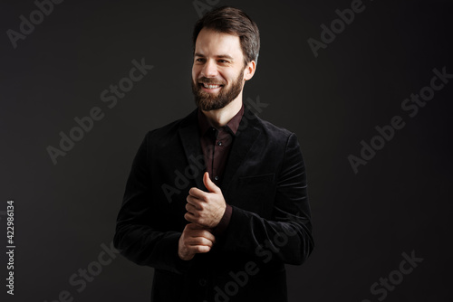 Bearded happy man in black jacket smiling and looking at camera
