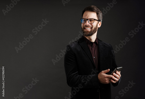 Bearded happy man in jacket smiling while using mobile phone © Drobot Dean