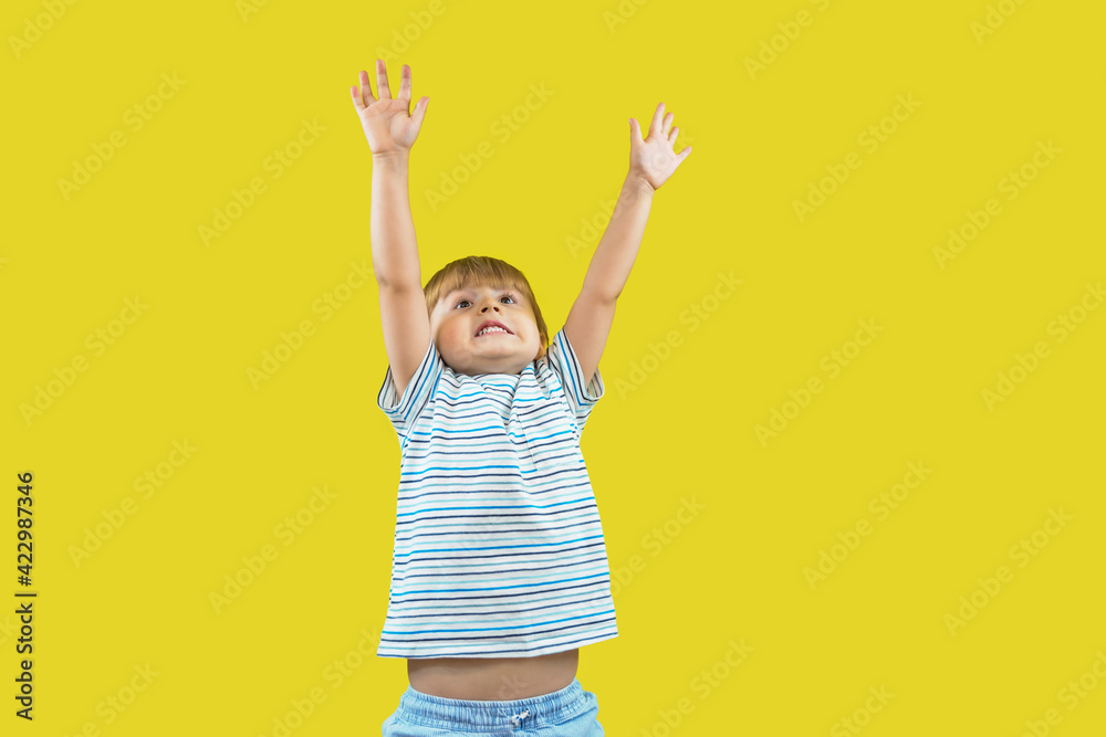 Toddler boy stretching and looking up, isolated on yellow background. Child raising hands and wants to grow. Mock up, copy space. Toddler boy stretching and looking up, isolated on yellow background. Child raising hands and wants to grow. Mock up, copy space.