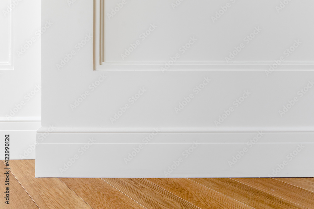 Fragment of classic white interior with wooden french herringbone parquet  floor and installed wall panels, decorated with moldings and skirting  boards. Final stage of finishing works in the apartment Photos | Adobe