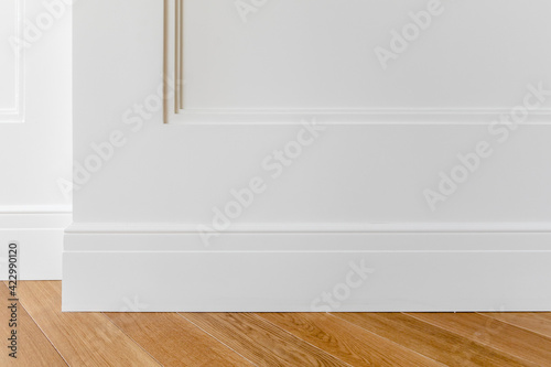 Принти на полотні Fragment of classic white interior with wooden french herringbone parquet floor and installed wall panels, decorated with moldings and skirting boards
