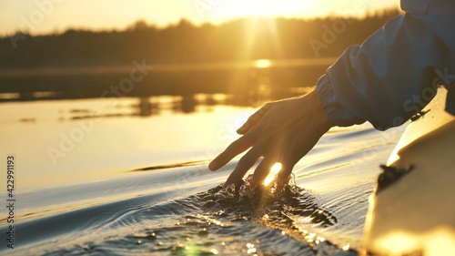 Leinwand Poster man puts fingers down in lake kayaking against backdrop of golden sunset, unity