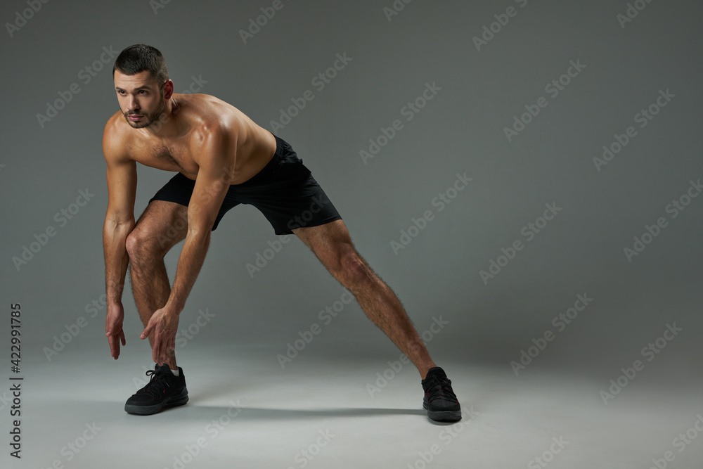 Strong athlete man with powerful torso warming up isolated on grey background Strong athlete man with powerful torso warming up isolated on grey background