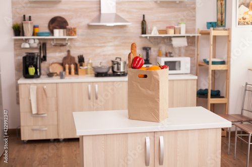 Paper bag filled with groceries on kitchen table top. Fresh and healthy lifestyle © DC Studio