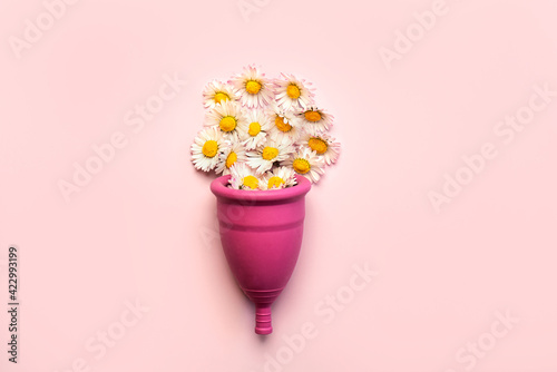 Silicone menstrual cup with white daisy flowers.Female intimate alternative gynecological hygiene concept photo