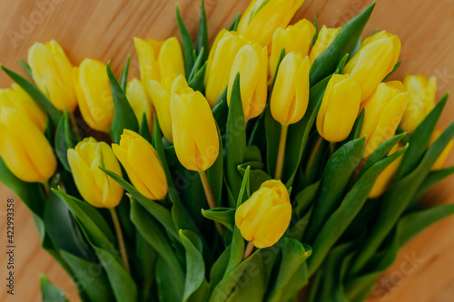 Bright fresh yellow tulips on wooden background. Many yellow tulips on wooden table. Bunch of flowers on the table.
