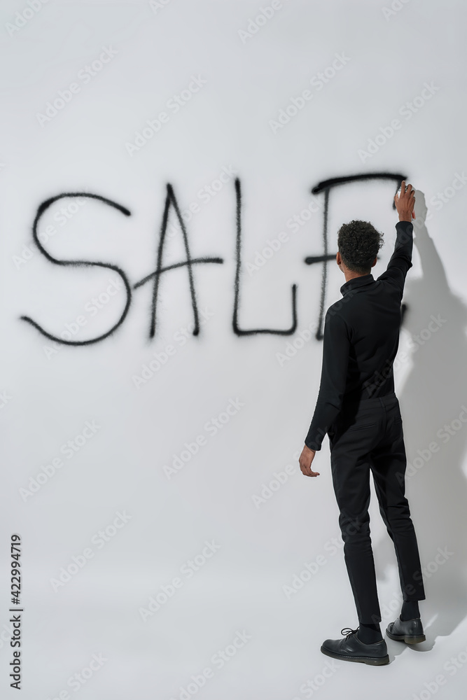 Rear view of young boy writing inscription sale on wall