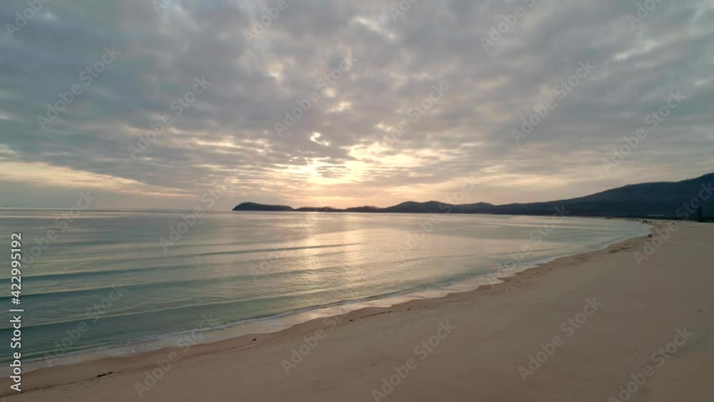Aerial view of beach with calm transparent sea water and sky reflection at sunset. Camera moves backwards Aerial view of beach with calm transparent sea water and sky reflection at sunset. Camera moves backwards