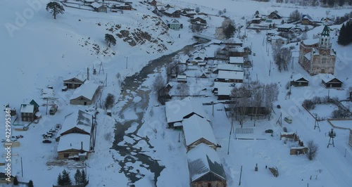 Aerial view of a village in the snow in winter on the bank of a frozen river