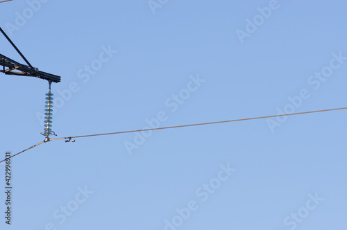 Closeup of a high voltage power transmission cable hanging on na  attachment point of a electricity pole  with a clear blue sky