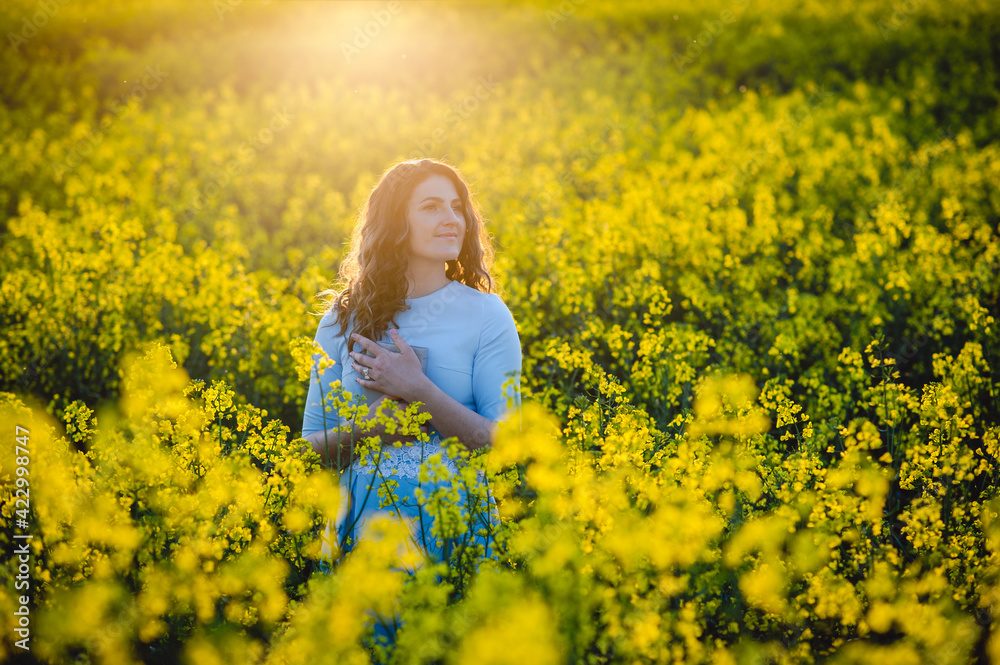 Fototapeta premium Happy girl hugs the bible in the sunlight on a background of yellow flowers. Girl with a book outdoors. Concept for faith, spirituality and religion. Peace, hope