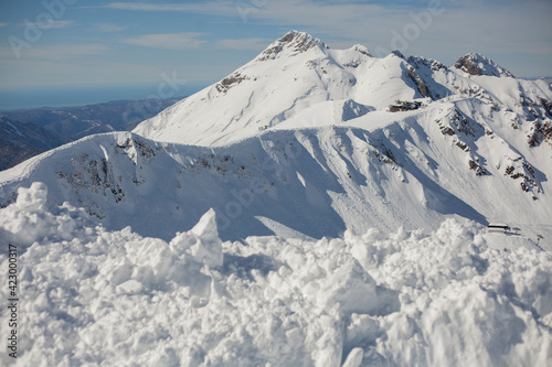 Snow Mountain. Caucasian ridge. Snowy slope. Wild mountainous place in the reserve. Mountain peak on a sunny day. The rock protrudes from the ground against the sky