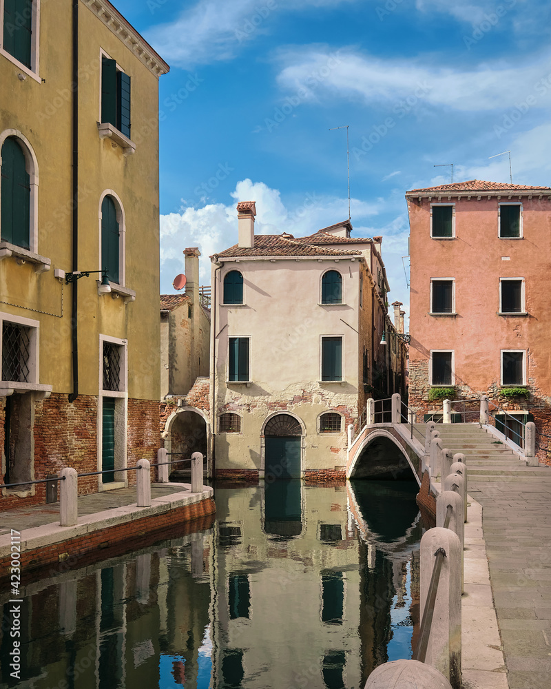 Romantic canals and waterways of Venice. Traditional Venetian bridge and old colorful buildings with reflections in sea water. Dorsoduro neighbourhood in Venice, Italy.
