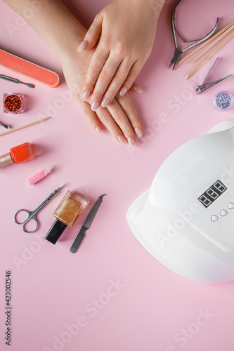 Spa procedure for nail care in a beauty salon. Female hands and tools for manicure on pink background. Bodycare concept.