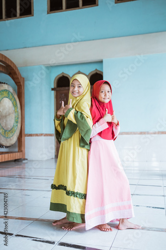 Kids woman Muslim pose and show thumbs looking at cameras in mosques © Odua Images