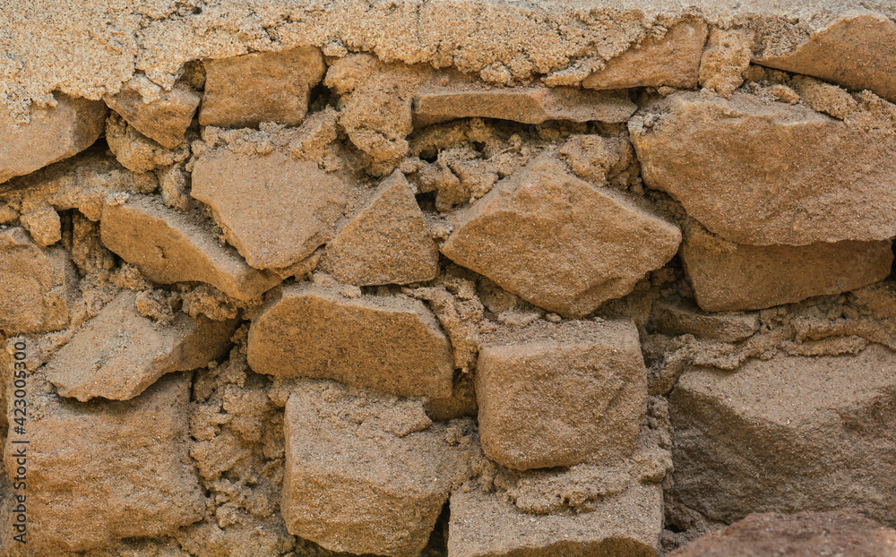 Fototapeta premium detail section of an dusty old broken stone wall, background texture, closeup of a dry crumbling stone wall