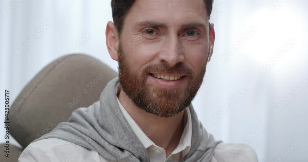 Portrait of Intelligent Man sitting in Office Room and looking at the Camera. Successful Bearded Businessman with Attractive Smile looking Confident. Working from Home Remote. Quarantine Concept. Portrait of Intelligent Man sitting in Office Room and looking at the Camera. Successful Bearded Businessman with Attractive Smile looking Confident. Working from Home Remote. Quarantine Concept.