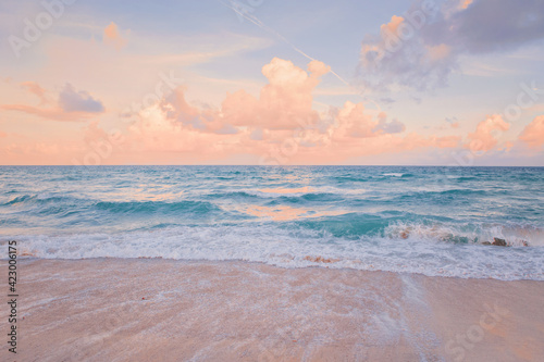 Sea ocean beach sunset sunrise landscape outdoor. Water wave with white foam. Beautiful sunset airy red sky with clouds. Natural aquatic blue pink turquoise aquamarine colorful background.