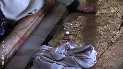 Belivers praying and putting cloth and souvenirs in the Holy Church of Sepulchre in Jerusalem on the rock where it is believed Jesus was laid before his burial photo