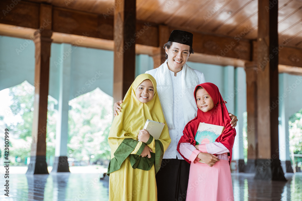 Portrait of an Muslim teacher and Muslim children holding the al quran book in a mosque