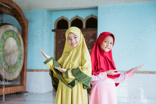 Two kid girl asian Muslim smiling showing something in mosques photo