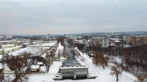 Speedup fly above river dam. Aerial view on winter Kharkiv frozen Lopan river covered in snow. photo