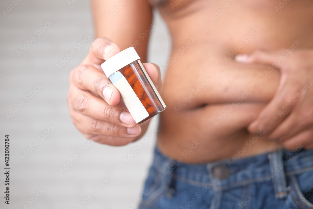 holding excessive belly fat and pill container with copy space holding excessive belly fat and pill container with copy space