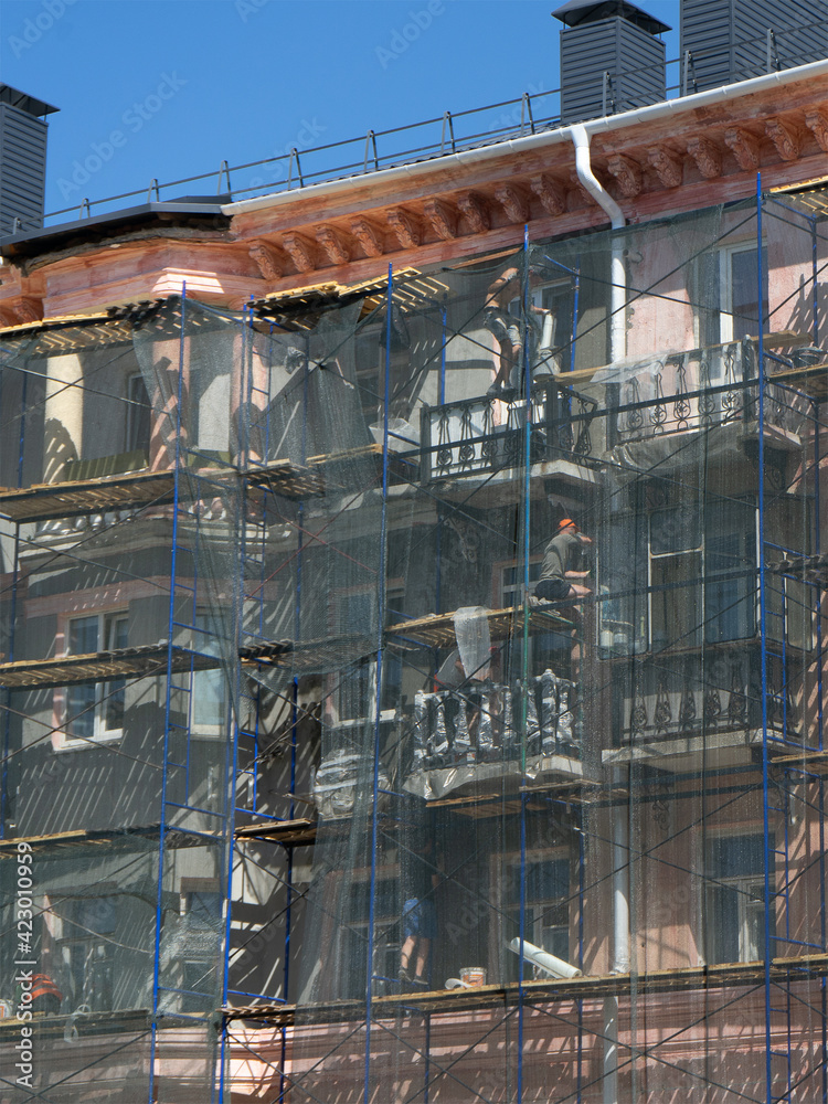 Scaffolding around the building, workers restoring the facade of the old building.