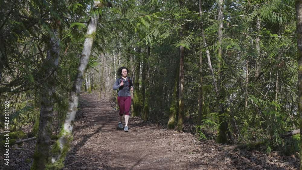 Caucasian Woman Trail Running in the Green Forest surrounded by beautiful trees. Taken in Squamish, British Columbia, Canada. Slow motion Caucasian Woman Trail Running in the Green Forest surrounded by beautiful trees. Taken in Squamish, British Columbia, Canada. Slow motion