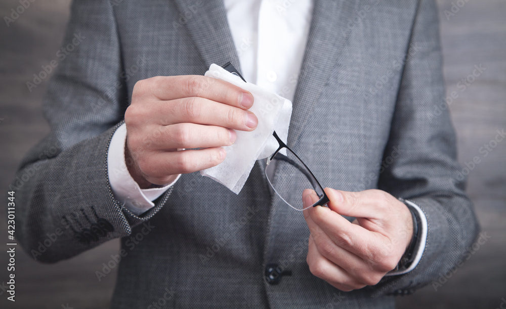 Businessman cleaning eyeglasses with wet wipe. Businessman cleaning eyeglasses with wet wipe.