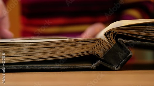 Elderly woman looks through an family album with old photos at table at home.