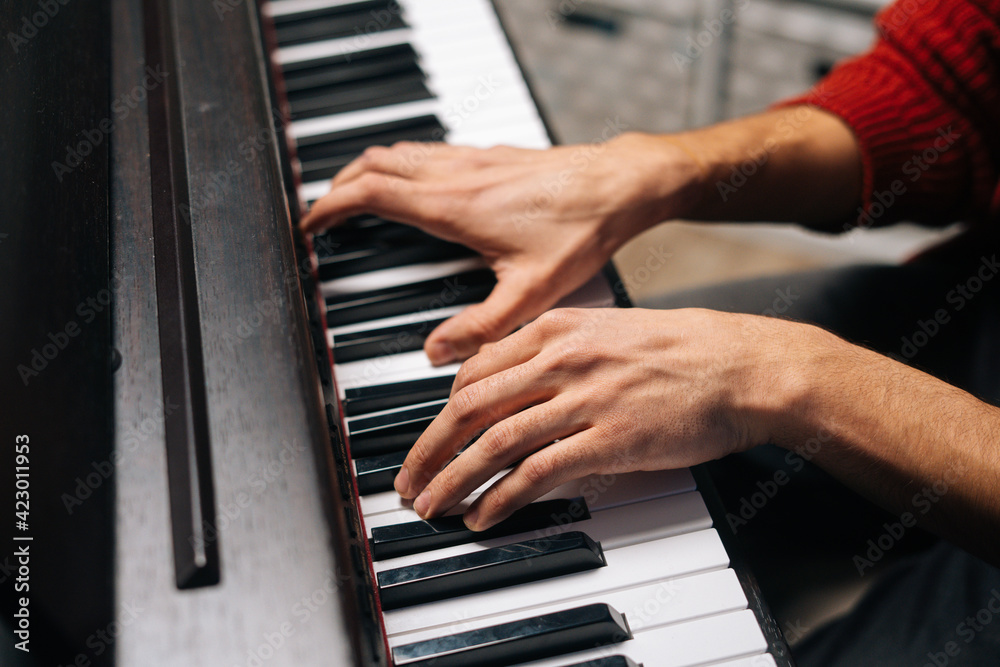 Close-up hands of unrecognizable musician man playing on digital electronic piano synthesize at home. Closeup side view fingers of pianist male playing on digital piano. Concept of music education. Close-up hands of unrecognizable musician man playing on digital electronic piano synthesize at home. Closeup side view fingers of pianist male playing on digital piano. Concept of music education.