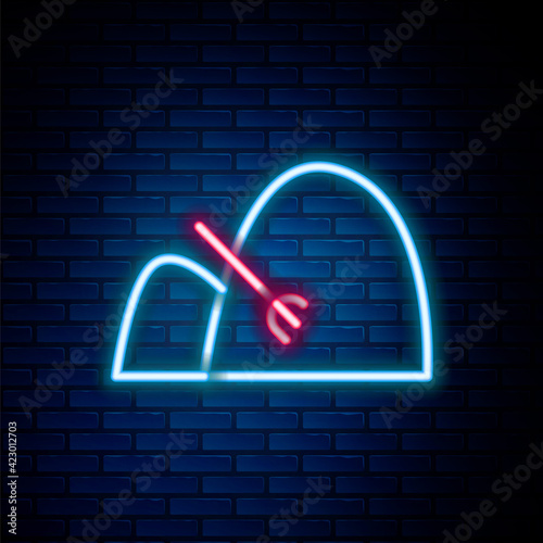 Glowing neon line Bale of hay and rake icon isolated on brick wall background. Colorful outline concept. Vector