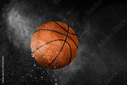Basketball ball flying in water drops and splashes isolated on black background