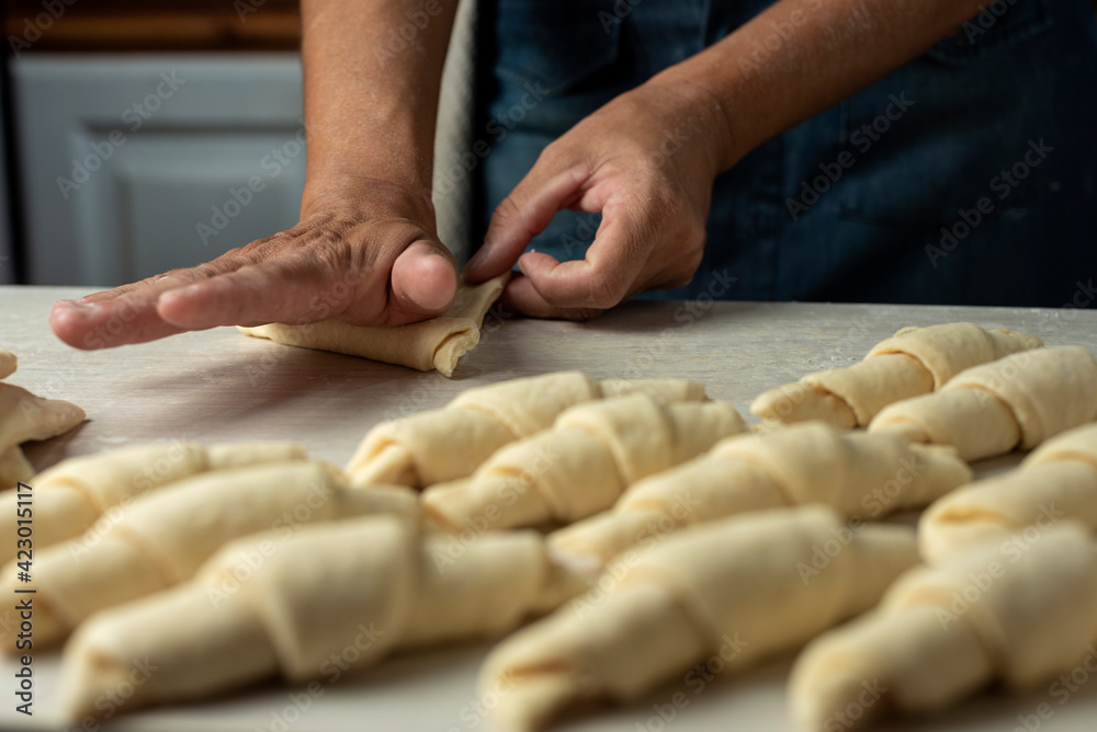 hands kneading croissants and croissants on wooden countertop