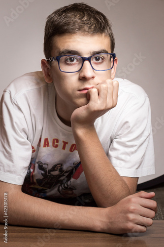 Young boy holding hand under head, looking upset