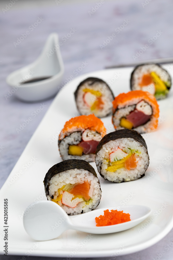 Sushi rolls with salmon, avocado and crab palm on a white plate with soy sauce Sushi rolls with salmon, avocado and crab palm on a white plate with soy sauce