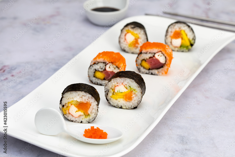 Sushi rolls with salmon, avocado and crab palm on a white plate with soy sauce Sushi rolls with salmon, avocado and crab palm on a white plate with soy sauce