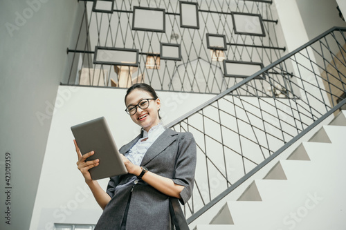 Portrait of young beautiful businesswoman holding at tablet standing in stairs office photo