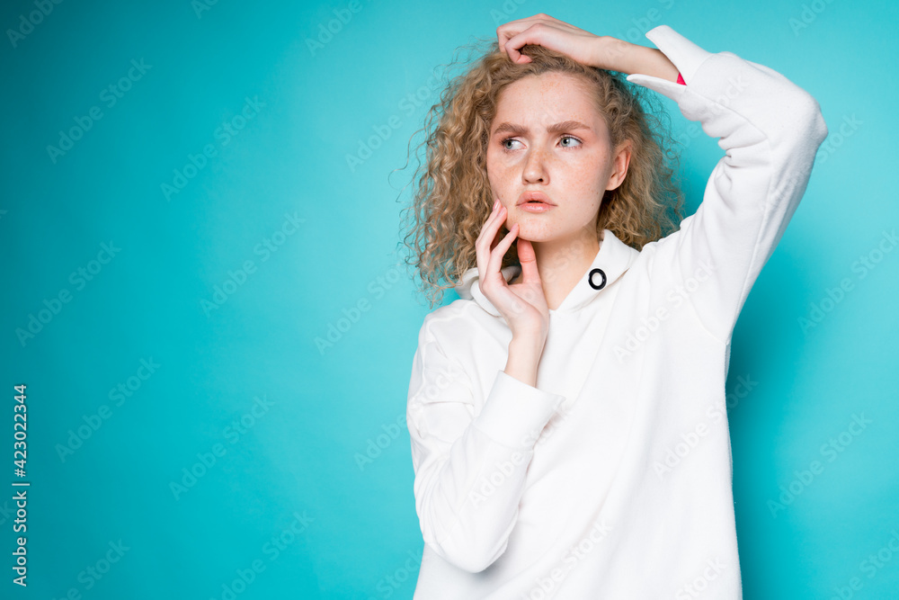 Beautiful sad girl in white clothes touches her face with her hands and looks to the side Beautiful sad girl in white clothes touches her face with her hands and looks to the side